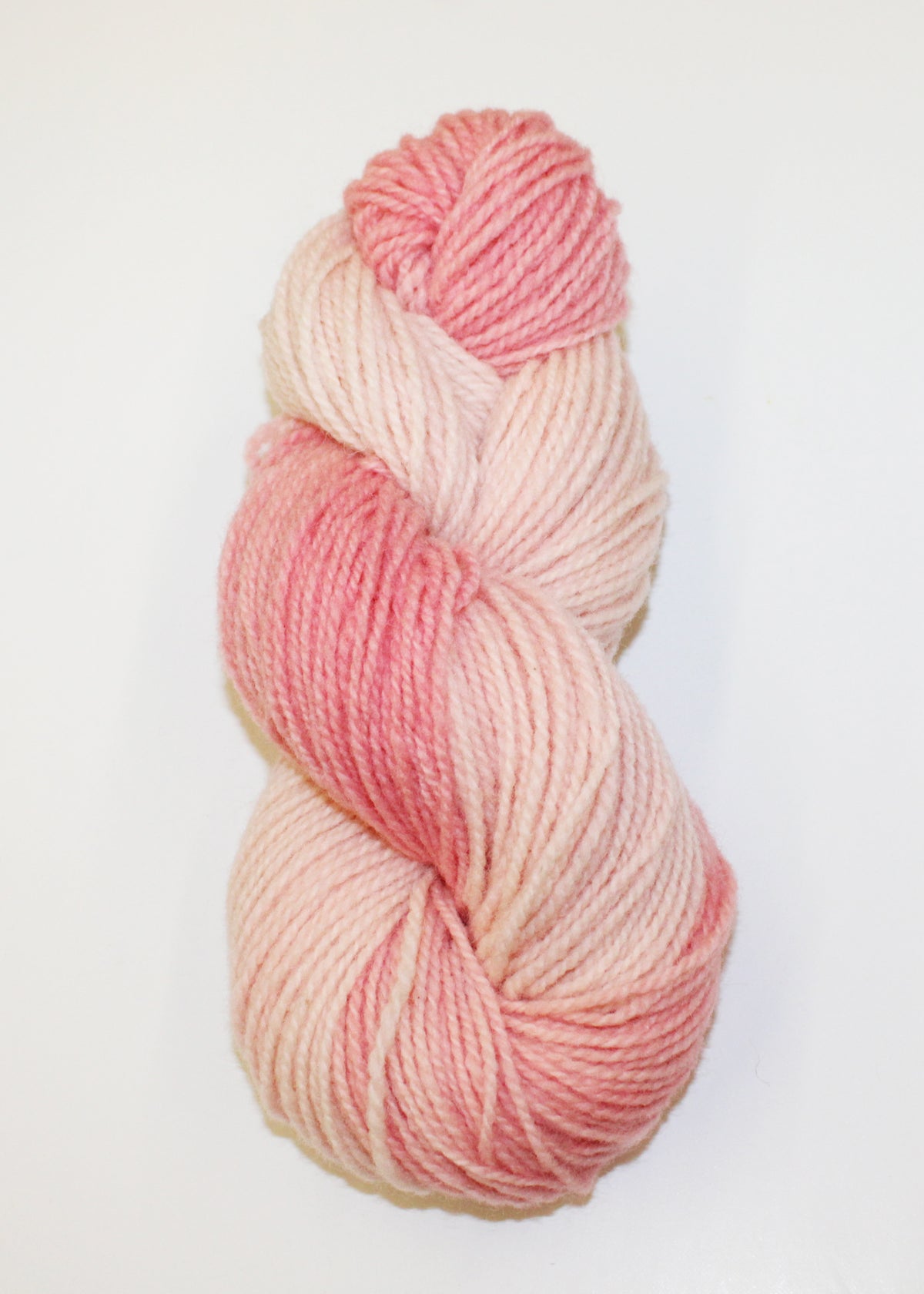 A single skein of variegated yarn in shades of pink and cream, photographed against a plain white background.