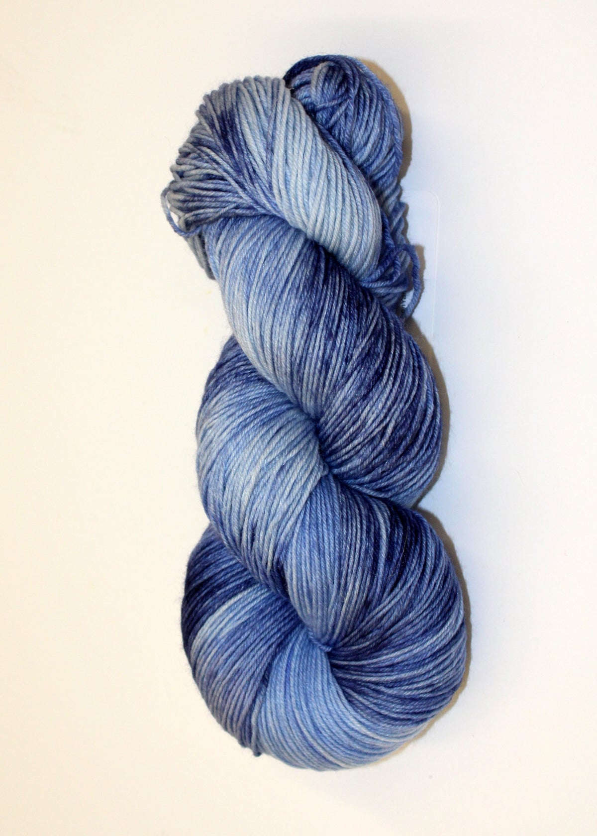 A single skein of variegated yarn in shades of blue and navy, photographed on a plain off-white background.